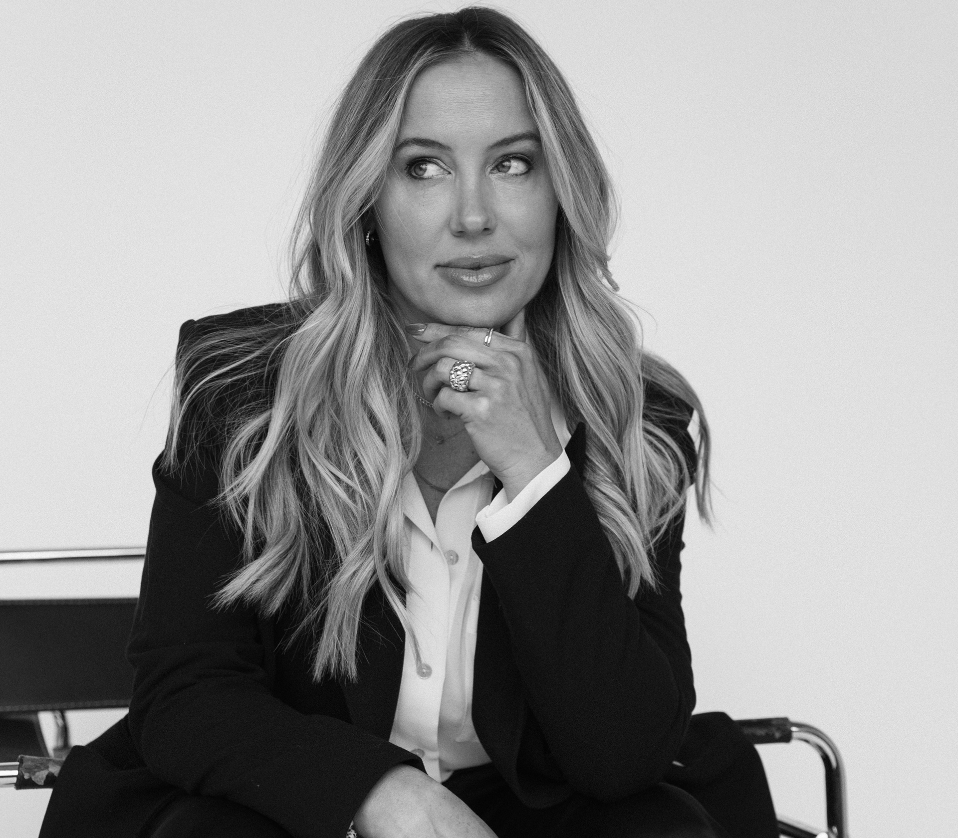 A thoughtful woman with long wavy hair in business attire.