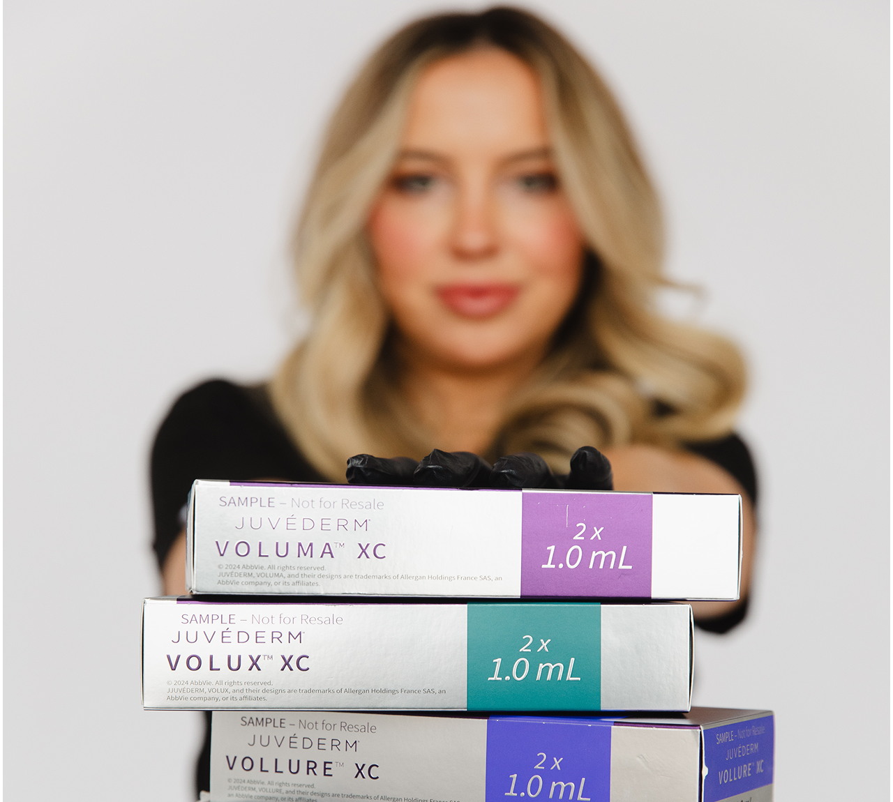 A woman holding Voluma XC skincare product boxes.